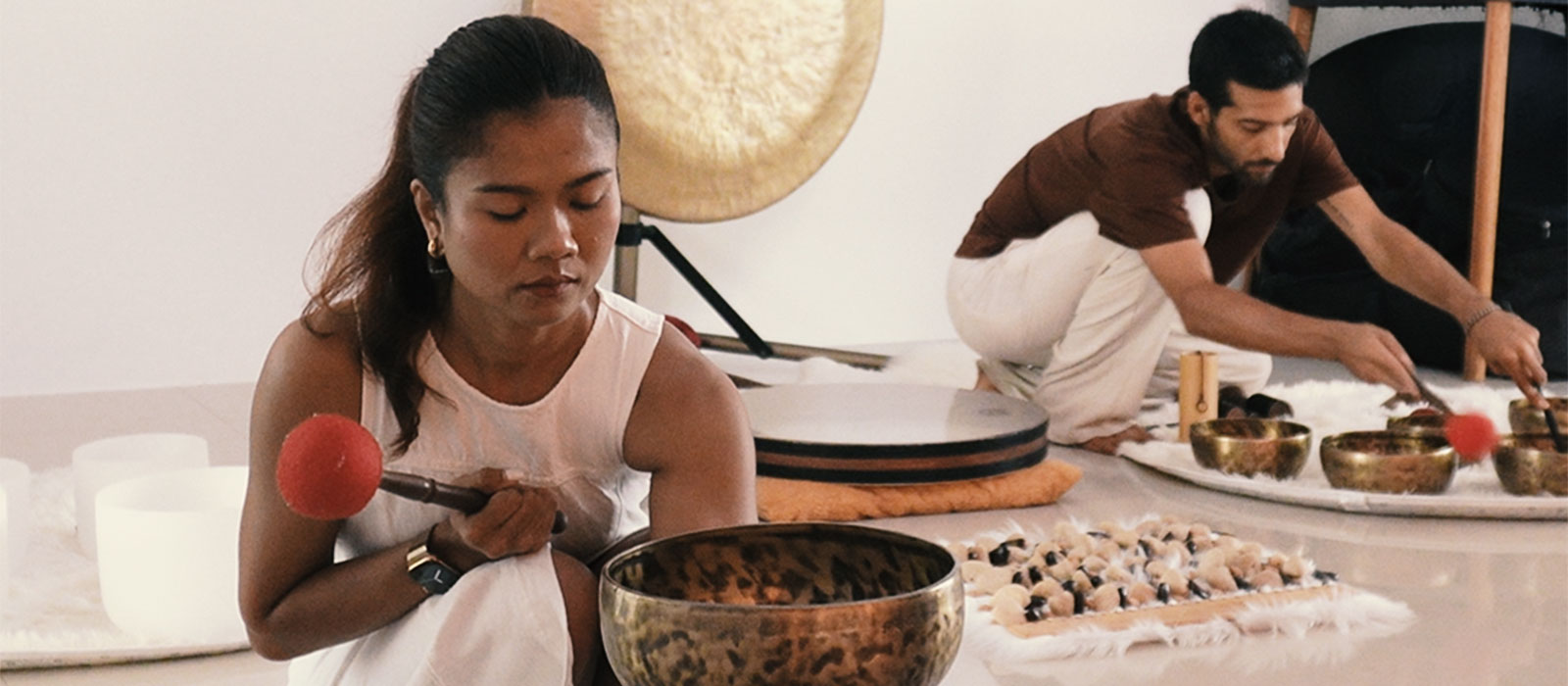 Melie and Can playing Tibetan bowls, gong and frame drum during a sound journey in Koh Samui